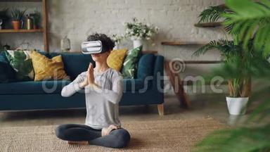 戴着虚拟现实眼镜的瘦女孩坐在家里的地板上，坐在莲花的位置上，享受着个人的乐趣